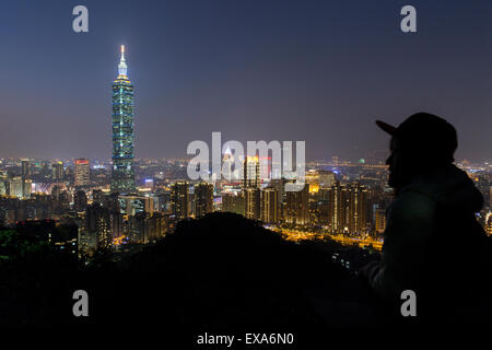 Asien, Taiwan, Taipei, Silhouette eines Besuchers auf Elefanten Berg mit Blick auf Skyline von Taipei 101 Hochhaus und Stadt in der Abenddämmerung auf Stockfoto