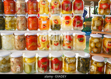 Eingelegte Paprika, Gurken, Zwiebeln und anderes Gemüse in Gläser mit lustigen Gesichtern, Bauernmarkt auf dem Plattensee, Ungarn Stockfoto