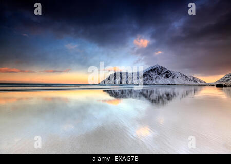 Sonnenuntergang am Skagsanden Strand, umgeben von schneebedeckten Berge spiegeln sich in den Meer, Flakstad, Lofoten, Arktis, Norwegen Stockfoto