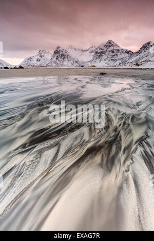 Sonnenuntergang am surreale Skagsanden Strand umgeben von Schnee bedeckt Berge, Flakstad, Lofoten-Inseln, Arktis, Norwegen Stockfoto