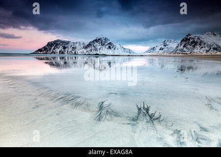 Sonnenuntergang am Skagsanden Strand, umgeben von schneebedeckten Berge spiegeln sich in den Meer, Flakstad, Lofoten, Arktis, Norwegen Stockfoto