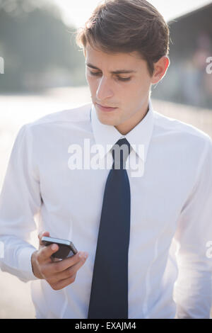 junge hübsche elegante blonde Modell Mann mit Smartphone in der Stadt Stockfoto
