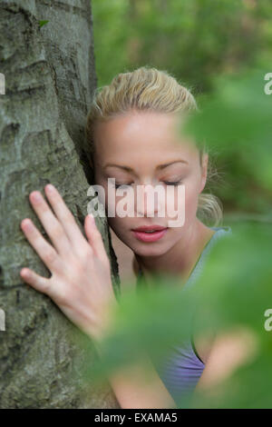 Junge Frau umarmt einen Baum. Stockfoto
