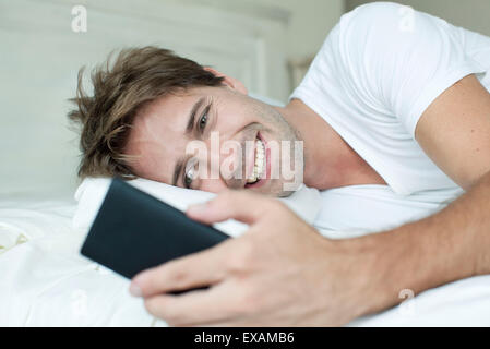 Mann im Bett mit smartphone Stockfoto