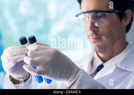 Wissenschaftler hinterfragen Reagenzgläser mit blauer Flüssigkeit im Labor Stockfoto