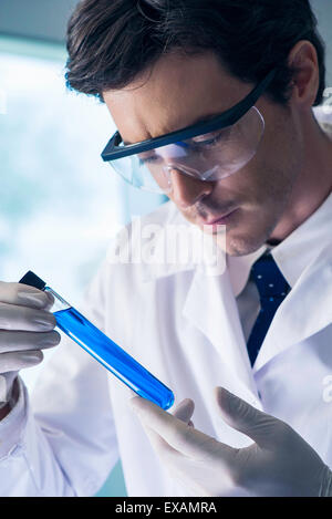 Chemiker Examing Reagenzglas mit blauer Flüssigkeit im Labor Stockfoto