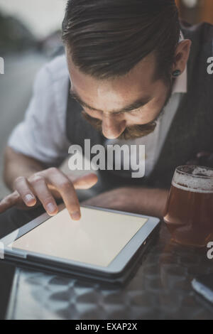 schöner großer Schnurrbart Hipster Mann mit Tablet sitzt an der bar Stockfoto