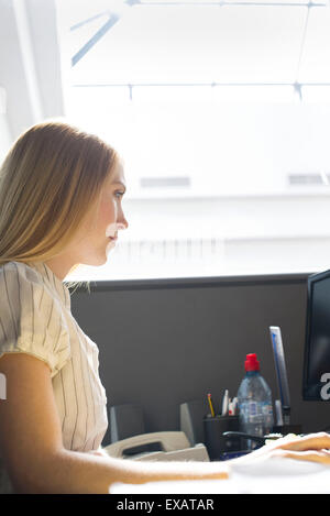 Junge Frau aufmerksam im Großraumbüro arbeiten Stockfoto