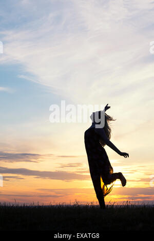 Teenager-Mädchen energetisch Spaß bei Sonnenuntergang herumspringen. Silhouette Stockfoto