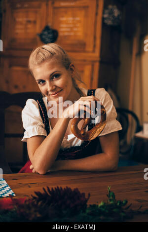 Frau sitzt am Tisch mit Maß Bier und Brezel Stockfoto