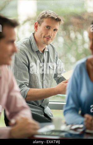 Mann sitzt im Café, Lächeln Stockfoto
