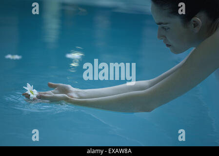 Frau für Blume im Pool schwimmend zu erreichen Stockfoto