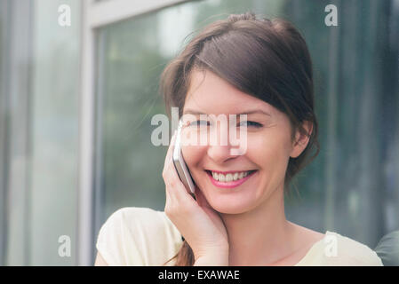 Fröhlich lächelnde Frau mit Handy, Stockfoto