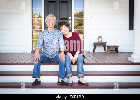 Attraktive Senior chinesischen Brautpaar sitzen auf den Stufen ihres Hauses. Stockfoto