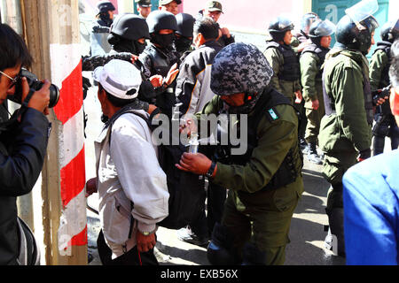 La Paz, Bolivien, 10. Juli 2015. Ein Polizist sucht bei einem Protest des Bürgerkomitees Potosi und seiner Anhänger die Tasche eines Passanten ab, bevor er die Plaza Murillo betritt (wo sich der Präsidentenpalast und die Kongressgebäude befinden). Die Demonstranten sind in La Paz, um von der Regierung die Einhaltung der Wahlversprechen zu fordern, die sie der Region in der Vergangenheit gegeben hat. Kredit: James Brunker / Alamy Live News Stockfoto