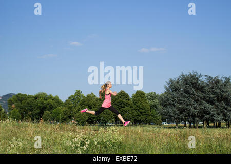 Blondes Mädchen, das im Sommer im Park läuft Stockfoto