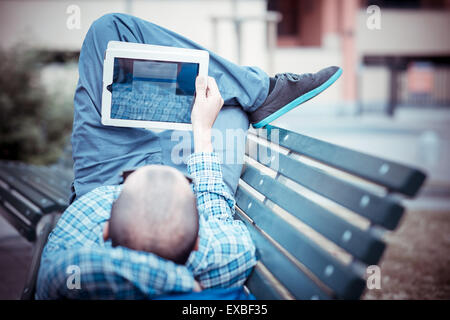 hübsche Hipster lässig Multitasking der moderne Mensch mit Tablet in der Stadt Stockfoto