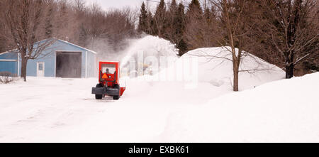 Kleine Snowblowing Traktor nimmt auf der Zufahrt nach einer langen Nacht Schneefall Stockfoto