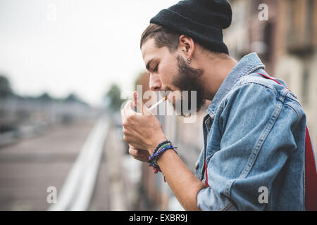 hübscher Junge bärtige Hipster Mann Rauchen Zigarette in der Stadt Stockfoto