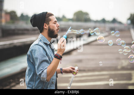 hübscher Junge bärtige Hipster Mann bläst Luftblasen Seife in der Stadt Stockfoto