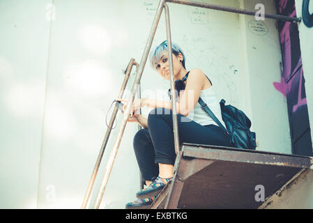 junge schöne kurze blaue Haare Hipster Frau mit Kopfhörern Musik in der Stadt Stockfoto