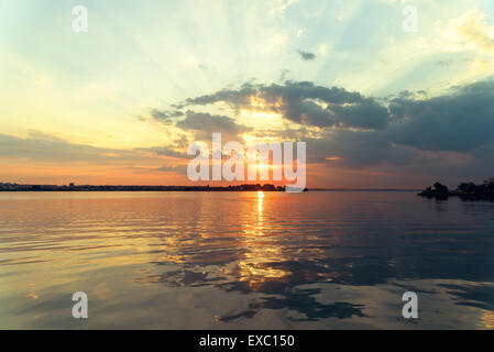 Rückwirkung der Sommer Sonnenuntergang mit schönen bewölkten Himmel über ruhige See Wasser Stockfoto