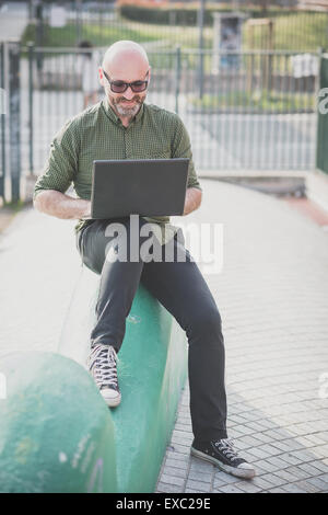 hübscher Mann mittleren Alters mit Notebook in der Stadt Stockfoto