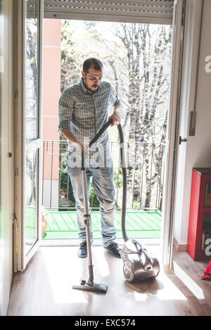 schöne stilvolle Mann mit Hoover zu Hause Stockfoto