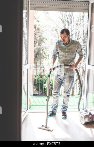 schöne stilvolle Mann mit Hoover zu Hause Stockfoto