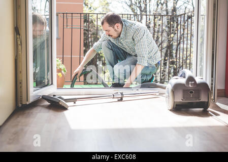 schöne stilvolle Mann mit Hoover zu Hause Stockfoto