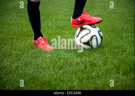 Nahaufnahme eines kleinen Jungen mit seinem Fuß auf einem Fußball Stockfoto