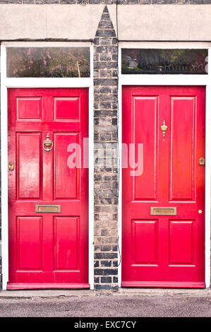 Benachbarte rote Front Holztüren in benachbarten Häusern in Großbritannien Stockfoto