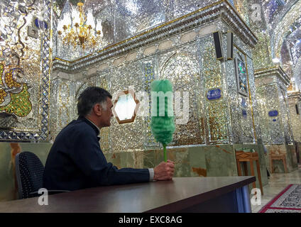 Wache mit einem grünen Staubwedel an der Shah-e-Cheragh-Mausoleum, Fars Provinz, Shiraz, Iran Stockfoto