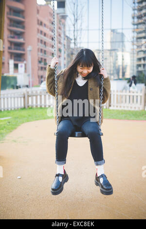 junge schöne asiatische Hipster-Frau in der Stadt - spielen auf einer Schaukel Stockfoto