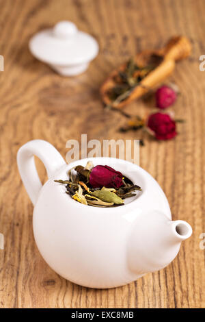 Grüner Tee mit Früchten, Gewürzen, Rosenblätter in weiße Teekanne Stockfoto