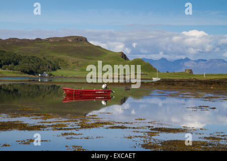 Kleines rotes Boot spiegelt sich in einer noch natürlichen Hafen auf der Insel von Canna mit Rhum in der Ferne. Stockfoto