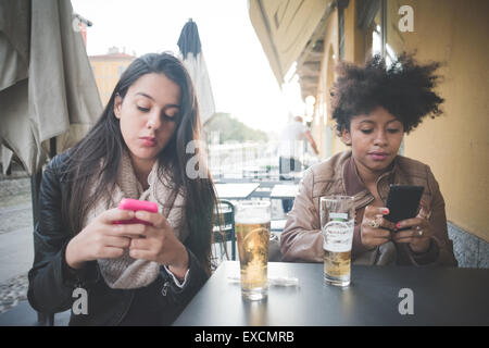 zwei multiethnischen schöne junge Frau Schwarz und kaukasischen mit einem Smartphone in der Stadt Stockfoto