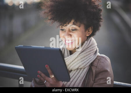 schöne schwarze Wuschelhaare Afrikanerin mit Tablet in der Stadt bei Nacht Stockfoto
