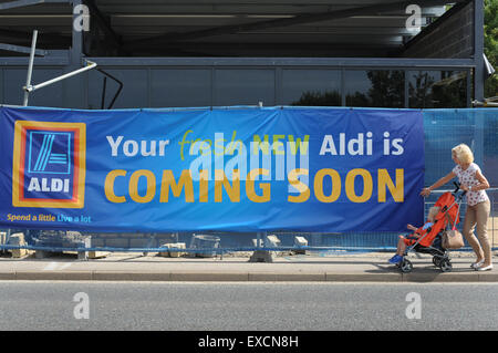 Eine Frau ein Baby im Kinderwagen schieben geht vorbei an einer neuen Aldi Supermarkt gebaut wird. Bild: Scott Bairstow/Alamy Stockfoto