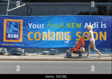 Eine Frau ein Baby im Kinderwagen schieben geht vorbei an einer neuen Aldi Supermarkt gebaut wird. Bild: Scott Bairstow/Alamy Stockfoto