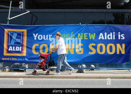 Ein Mann ein Baby im Kinderwagen schieben geht vorbei ein neuer Aldi Supermarkt gebaut wird. Bild: Scott Bairstow/Alamy Stockfoto