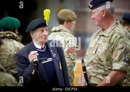 TAG DER STREITKRÄFTE IM STADTZENTRUM VON MANCHESTER.  eine alte veteran Soldat Chats mit uniformierten Soldaten Soldat Armee Stiefel Schlacht camouf Stockfoto