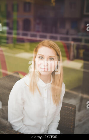 junge schöne blonde glatte Haare Frau in der Stadt sitzen im restaurant Stockfoto