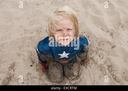 Ein vier Jahre alter Junge in einem Captain America Kostüm spielt an einem Sandstrand am Lake Michigan. Stockfoto