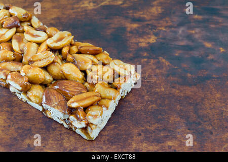 Honig-Bar mit Erdnüssen Mandeln und Haselnüsse auf einem braunen Holzbrett Stockfoto