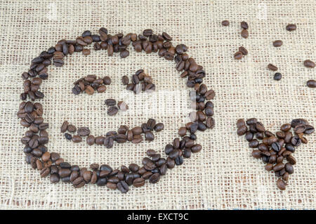 Smiley-Gesicht und Herz-Form gebildet vollständig aus Kaffeekörner auf Kaffee Tasche Textur gelegt Stockfoto