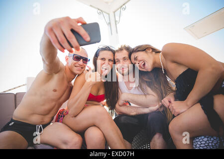 Gruppe von multiethnischen Jugendliche Frauen und Männer an der Strandbar im Sommer mit Smartphone unter selfie Stockfoto