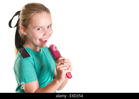 Junges Mädchen vorzugeben, dass ihre Haarbürste ein Mikro-Telefon und Gesang ist. Stockfoto