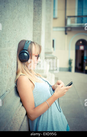 schöne blonde Frau anhören von Musik in der Stadt Stockfoto