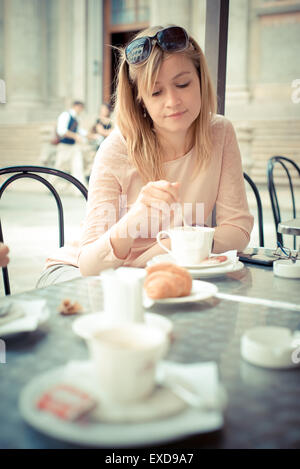 schöne blonde Frau mit Frühstück an der Bar in der Stadt Stockfoto